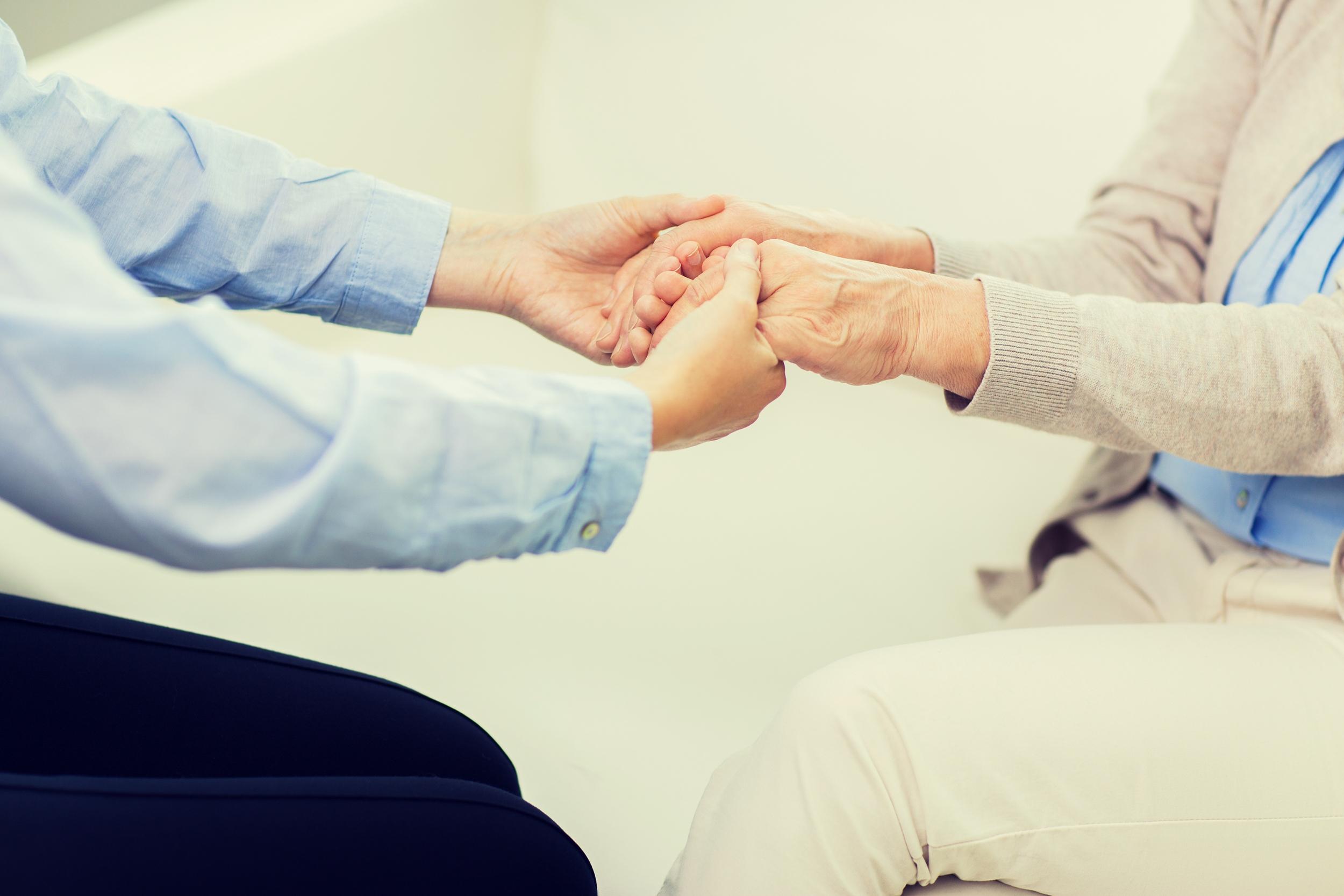 people, age, family, care and support concept - close up of senior and young woman holding hands